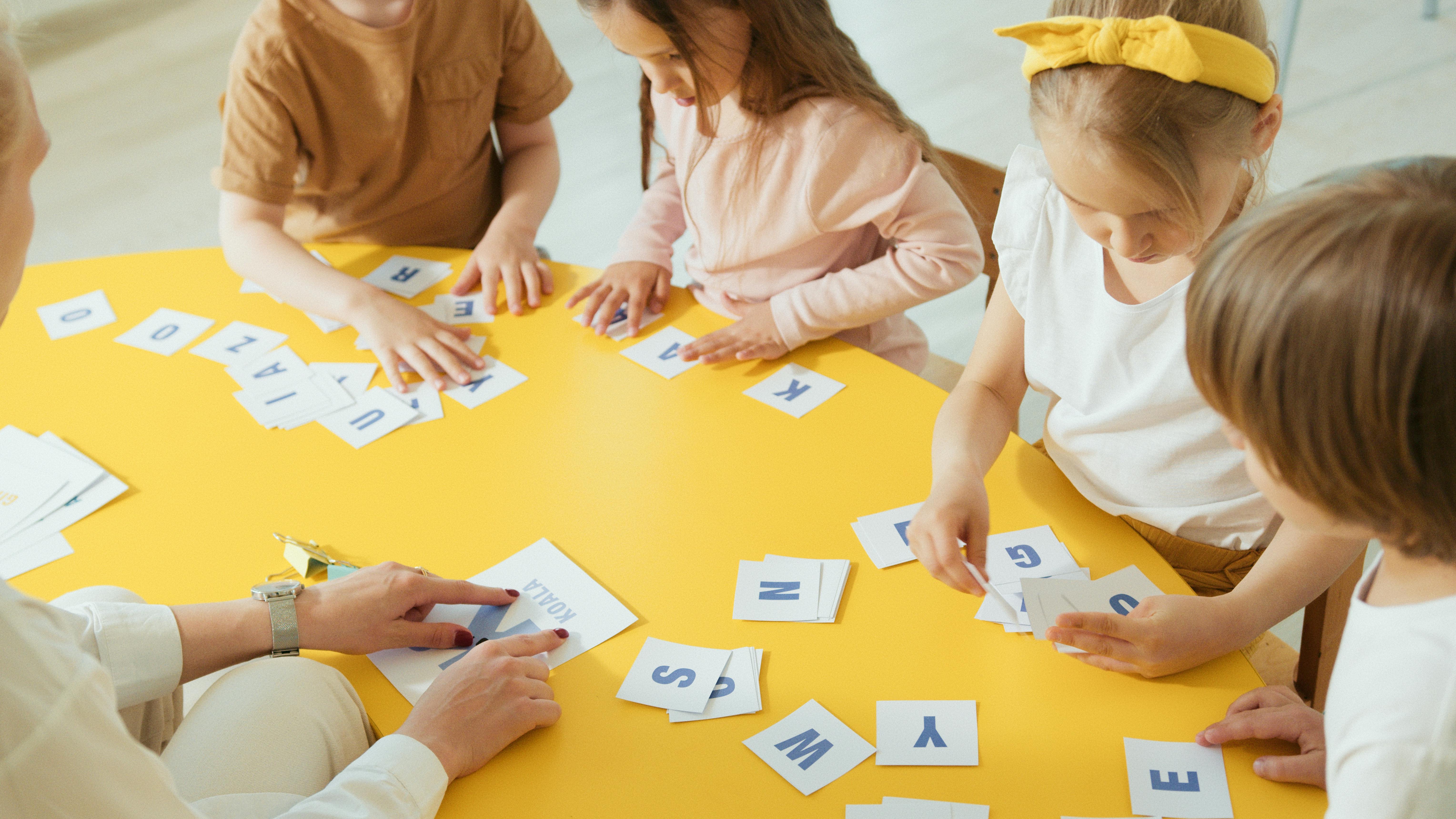 Children and teacher working together with letter cards around a table
