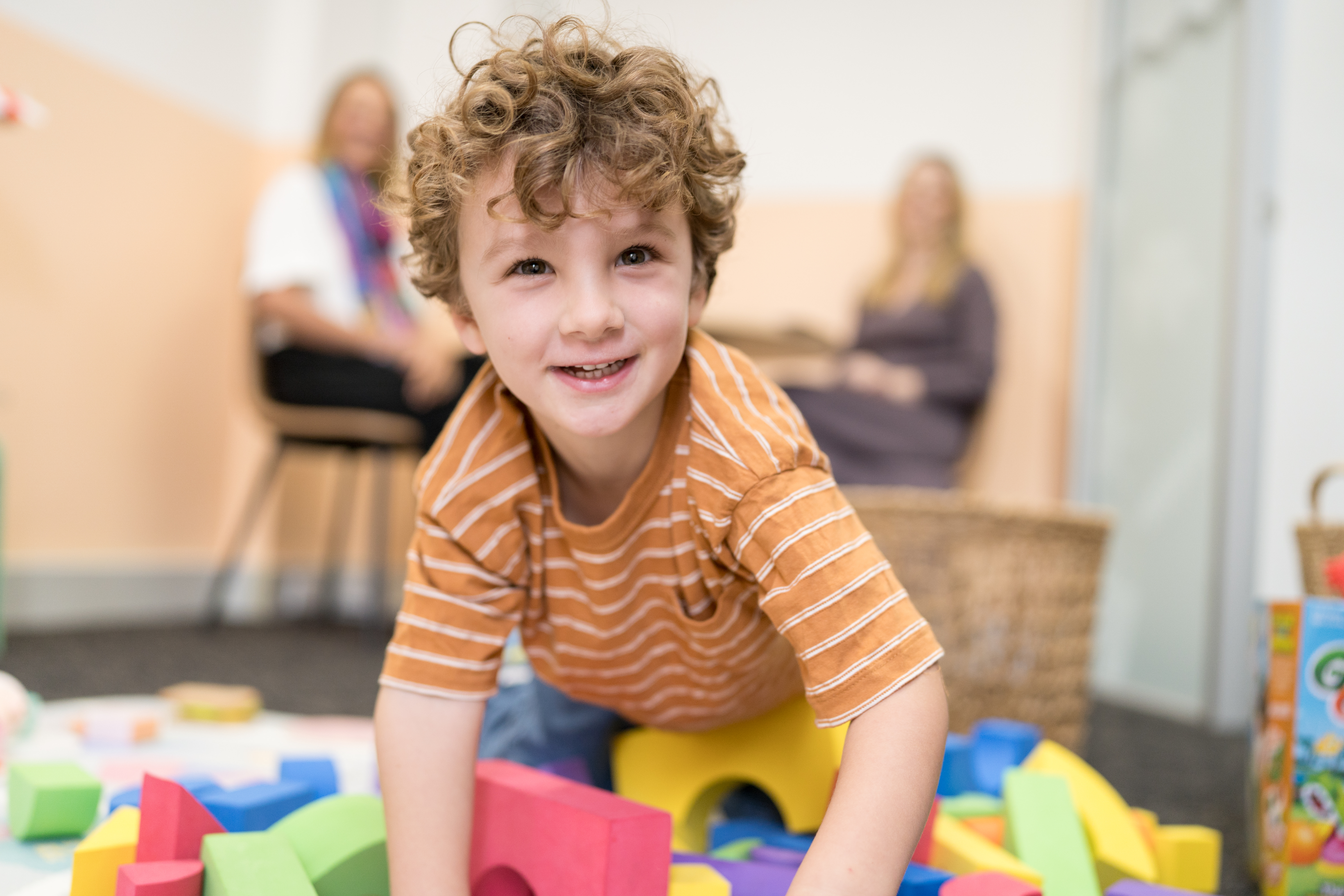 Young boy smiling and playing with colourful building blocks